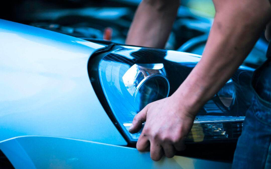 Un homme remplace le phare d'une voiture spéciale, zoom sur ses bras.